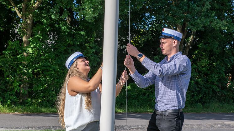 Katja Weibrecht Byrialsen og Nicolai Risager hejser flaget på Campus Mariagerfjord