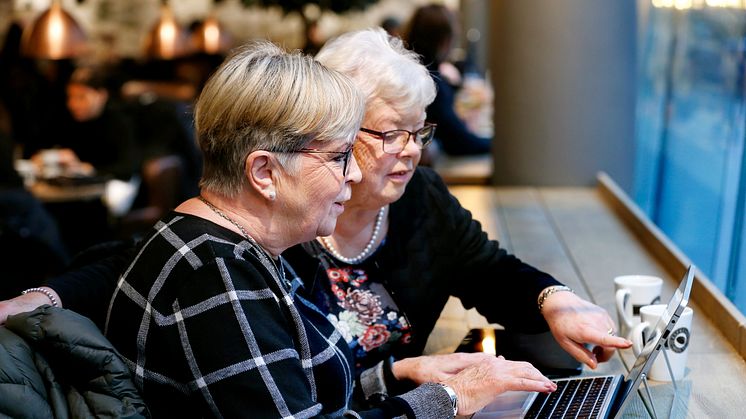 Två seniorer som surfar på ett café