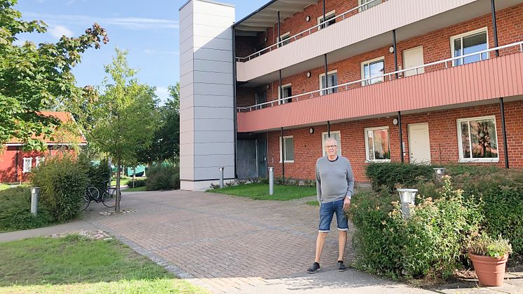 Lenny Petersson, ordförande i Brf Mönsteråshus 1, framför ett av föreningens hus som numera har en utanpåliggande hiss.