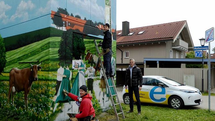 Heimatverbundenheit ziert Turmstation: Bayernwerk-Kommunalbetreuer Alexander Usselmann (rechts) besuchte die Art-EFX-Künstler Markus Ronge (links) und Pascal Sturm (Mitte) bei der Fertigstellung des Kunstwerks in Otterfing.