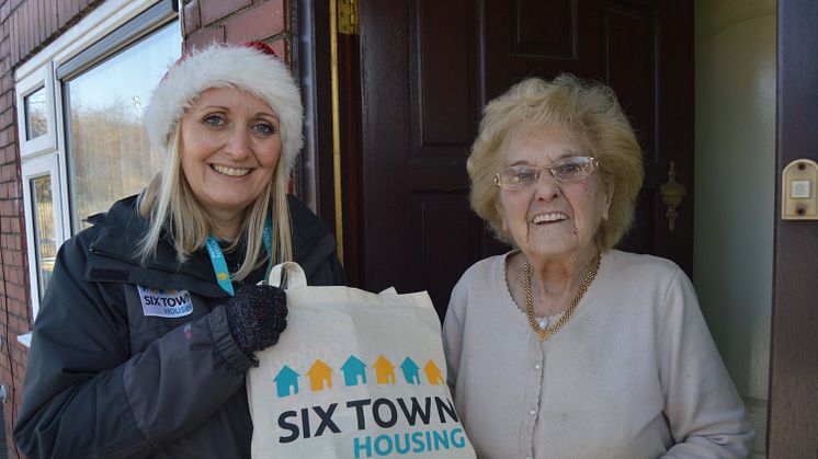 Six Town Housing community development worker Debbie Standring presents a Winter Warmers parcel to Radcliffe tenant Lily Shephard.