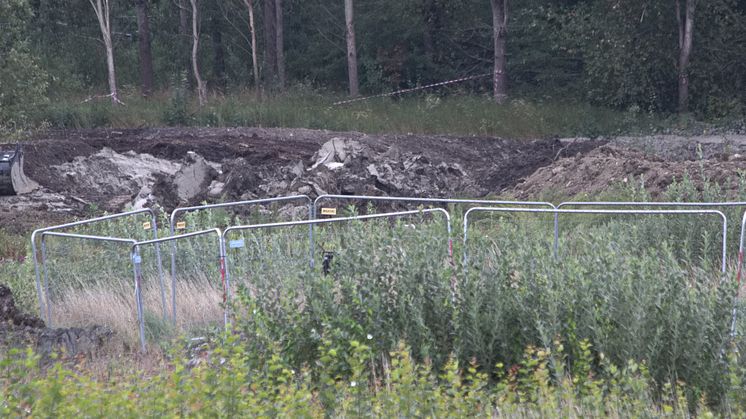 Området för den planerade reningsdammen består av lera och gyttja. Platsen där en grävmaskin sjönk och välte är inhägnad med byggstängsel. Bild tagen med teleobjektiv eftersom kyrkogårdsförvaltningen inte tillåter fotografering inne i arbetsområdet.