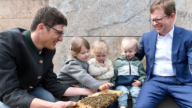 v.l.: Imker Dr. Jürgen Brandl probiert zusammen mit Clara, Ferdinand und Peer, sowie Vorstandsmitglied Dr. Bernd Hochberger den Stadtsparkassen-Honig. Die drei Kinder gehen in die sparkasseneigene Krippe vor Ort.