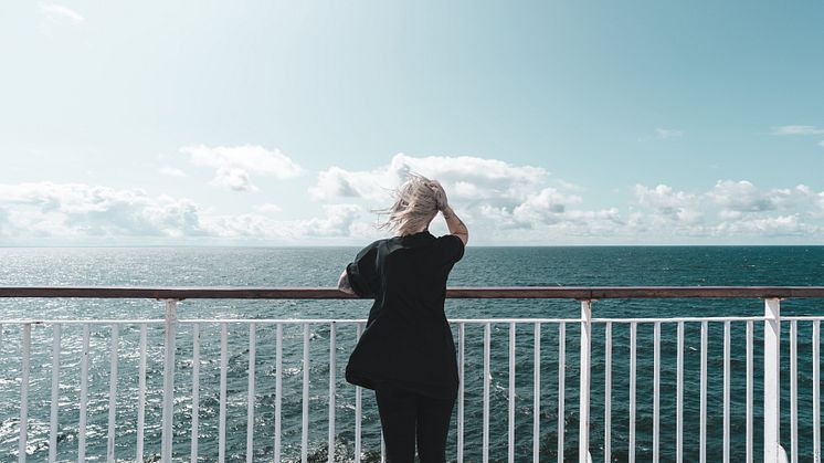 Young woman on deck looking over the sea