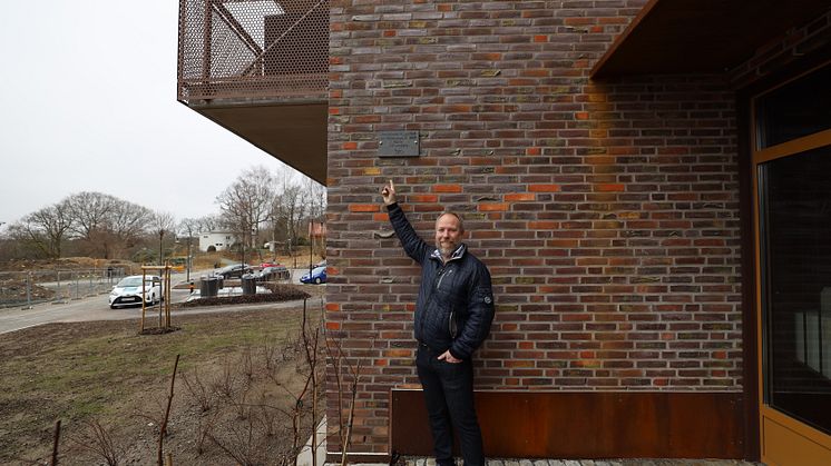 Ulf Lundberg visar sin namnplakett vid Wallenstams nyproducerade fastighet Kvarteret Rosengången i Mölnlycke Fabriker.