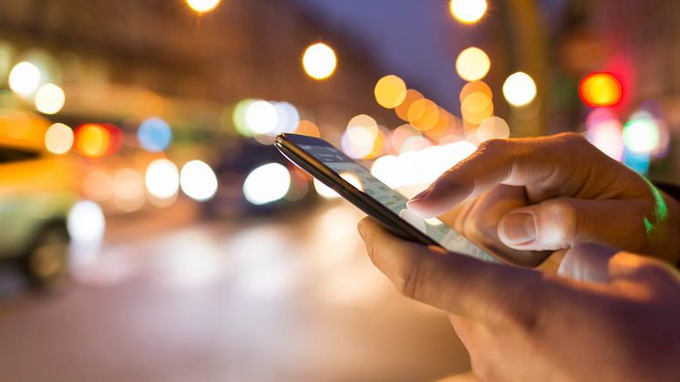 a man typing a number on his phone at night