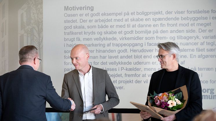 Jan Nymark Thaysen (t.v.), formand for Komitéen for Bygningspræmiering, overrækker CALUMs CEO, Cato Barslund (midt) prisen for Oasen-boligerne, flankeret af arkitekt Ole Madsen fra Kjaer & Richter (t.h.).