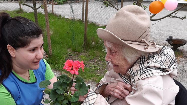 Personal och hyresgäst på Förenade Care Victoria ute i trädgården för att köpa fina blommor från butiken.