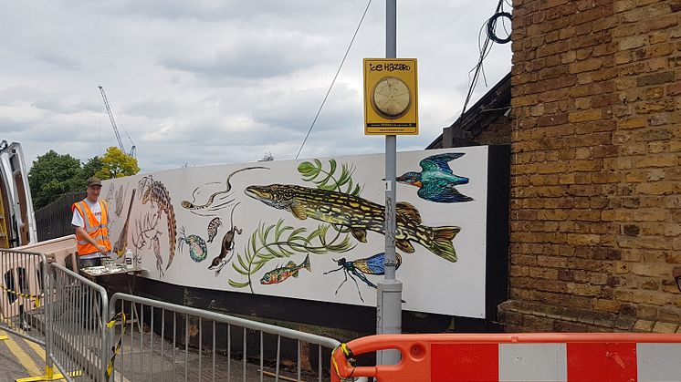 Mark Anthony of ATM Street Art painting the new mural at Palmers Green station - MORE IMAGES AVAILABLE TO DOWNLOAD BELOW