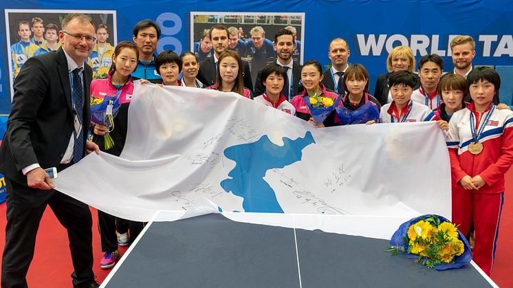 Det förenade Koreas VM-bronslag visar upp den historiska flaggan tillsammans med representanter för Halmstads VM-organisation.