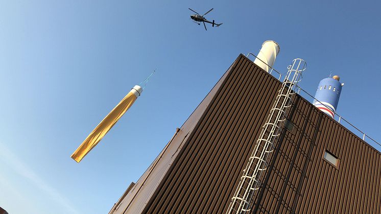 Nu är ventilationskanalen på plats i den 120 meter höga skorstenen på Västhamnsverket. Här lyfter helikoptern med del två, en del av ventilationskanalen samt huva. FOTO: Timo Julku, RKLM