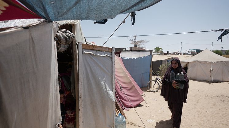Duaa Abu Sabha håller i vattenflaskor medan hon går till sitt tält i Al-Mawasi-området i Khan Yunis. Här delar nu minst 500 000 personer på 121 toaletter. Foto: Alef Multimedia/Oxfam