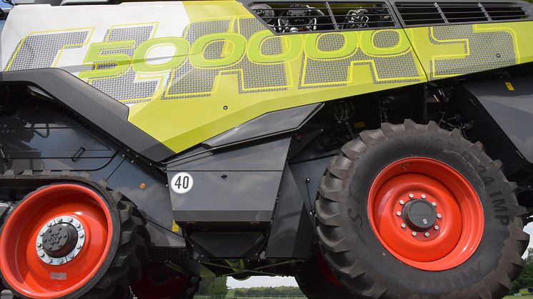 The CLAAS lettering is partially transparent thanks to the punched-out knotter hook pattern, the seed green “500000” stands out from the metallic paintwork of the machine.