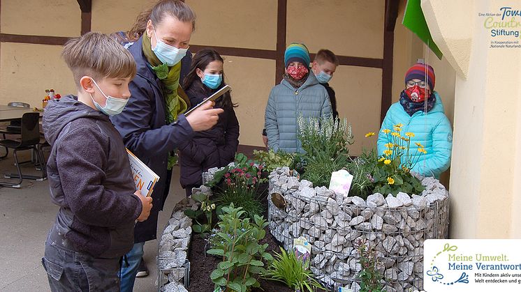 Hort-Leiterin Manuela Schildhauer freut sich mit den Kindern über die NektarTankstelle und das WildbienenHaus