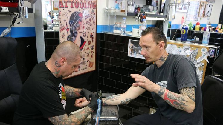 Örjan (t.h.) blir tatuerad av Rancids gitarrist Lars Frederiksen i London.