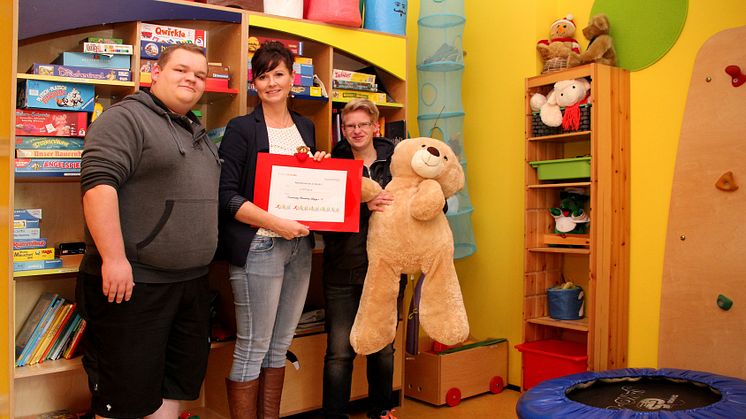 Norman Eilert (Azubi), Josephine Hermanns (Pflegepädagogin) und Sophie Lathan (Azubi) mit Spendenscheck im Geschwisterzimmer des Kinderhospizes