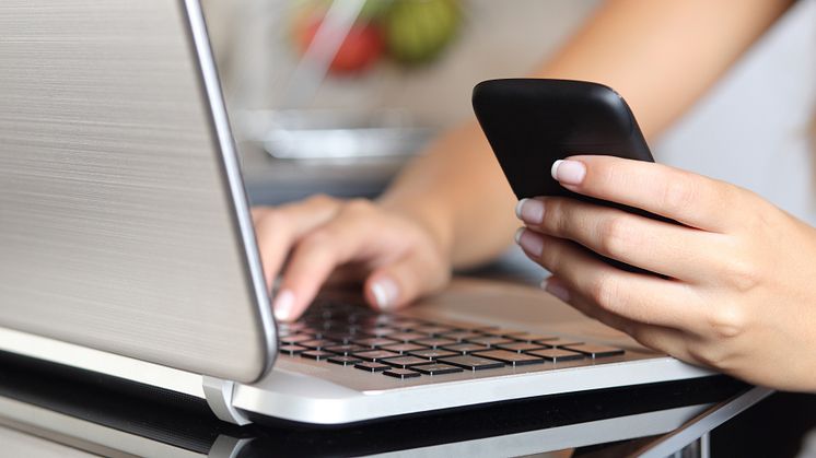 9994506-woman-hand-using-a-smart-phone-and-typing-a-laptop-at-home