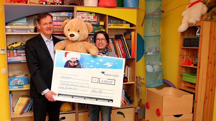 Mario Hesse von Baker Tilly überreicht Kerstin Stadler im Kinderhospiz Bärenherz den Spendenscheck
