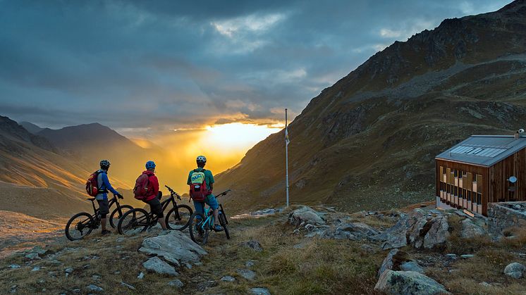 Mountainbiker genießen den Sonnenuntergang vor der Kesch Hütte (Graubünden), © Engadin St. Moritz. By-line: Swiss-image.ch / Fotograf Filip Zuan.