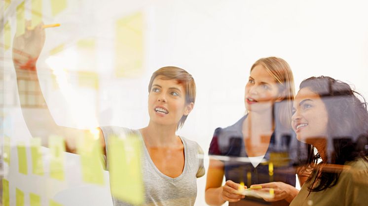 Woman drawing in the board to her coworkers