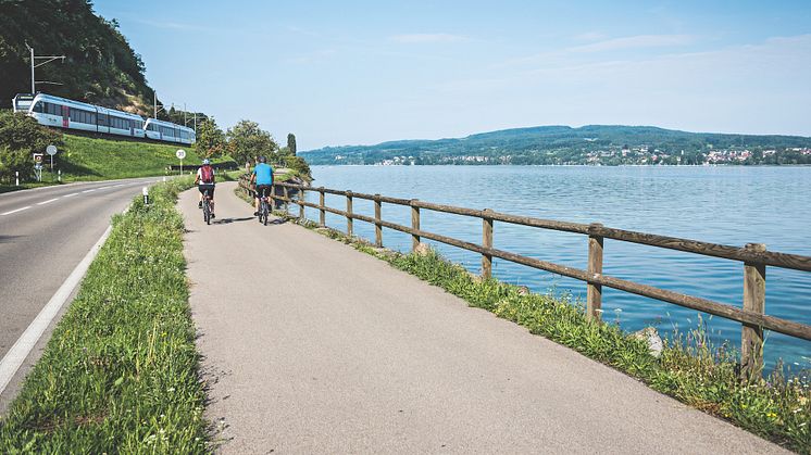 Tourenbiker unterwegs am Bodensee bei Berlingen. Im Hintergrund der Thurbo Zug, ©Schweiz Tourismus