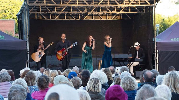 Föreställningen The Visitors bjöd på ABBA-musik för 1300 personer i Haninge kommun. Fotograf: Gunilla Cullemark. Syntolkning: Fem personer på scen med mikrofoner och instrument framför en stor publik.  
