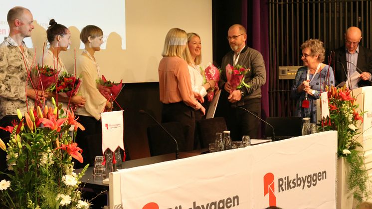 Johan Lindholm, ordförande i Riksbyggen, delar ut blommor till stipendiaterna.