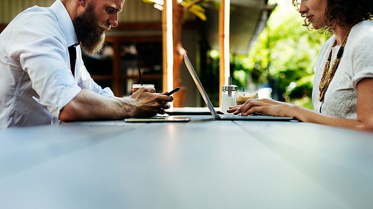 Mann og kvinne som bruker laptop og mobil paa cafe