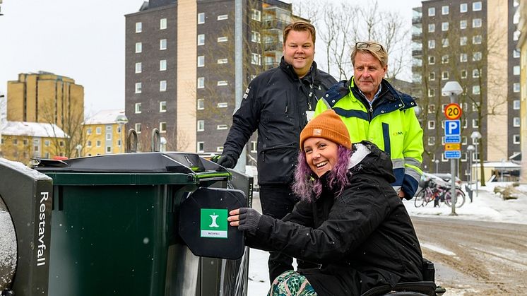 Hyresgästen Sandra provar ett nytt tillgänglighetsanpassat matavfallskärl. I bakgrunden syns Johan Paulsson, Helsingborgshem och Göran Svensson, NSR. Foto: Helsingborgshem.