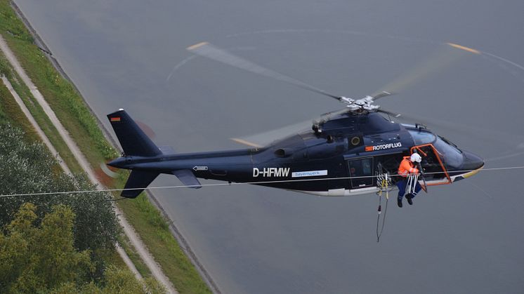 Aus dem Hubschrauber heraus montiert eine Spezialfirma am Donnerstag, 16. Juli, im Auftrag der Bayernwerk Netz GmbH Vogelschutzmarkierungen auf einer Hochspannungsleitung in Ingolstadt. Foto: Günter Drewnitzky