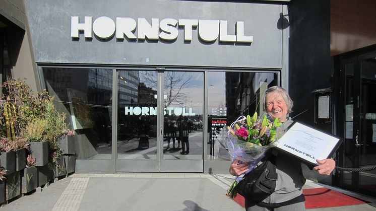 Lilleba Huttunen tar emot utmärkelsen framför entrén till Hornstulls handelsplats 