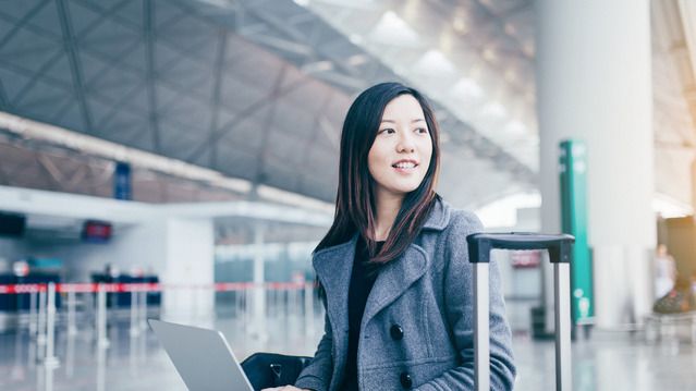 Woman using laptop and looking away at airport-2