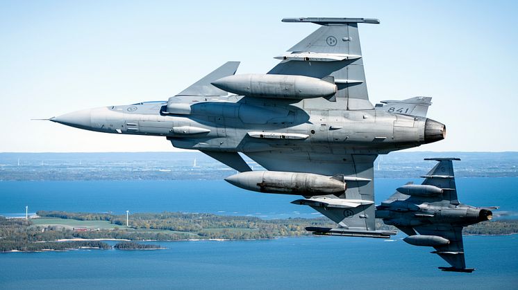 JAS 39 Gripen som flyger över ett område med vindkraftverk. Foto: Antonia Sehlstedt/ Försvarsmakten