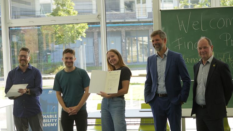 Eine Teilnehmerin (Mitte) der SMA 2023 bei der Zertifikatsübergabe durch Dr. Jeffrey Wolf vom Organisationsteam, Nicolas Schüte und Prof. Christian Rudolph vom Studiengang Radverkehr sowie Jörg Jenoch, Bürgermeister von Eichwalde (v. l. n. r.).