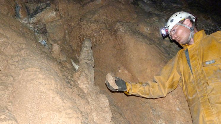 Prof Sebastian Breitenbach inside the cave with a stalagmite