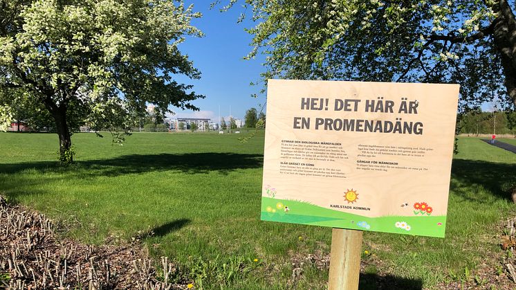 Skylt om promenadäng vid grönyta på Orrholmen.