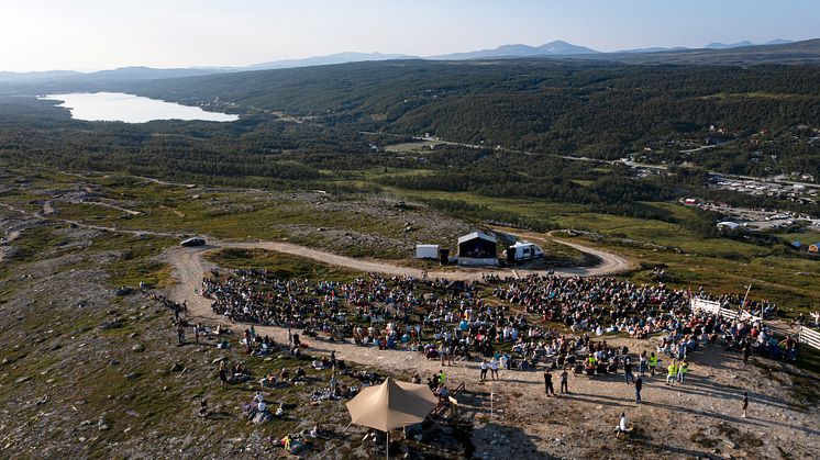 Publik som njuter av musik under en varm sommarkväll på fjället i Tänndalen.