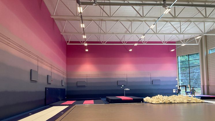 Hall för truppgymnastik med högt i tak och särskild färggradering på väggen, för gymnasternas möjlighet att orientera sig i luften.