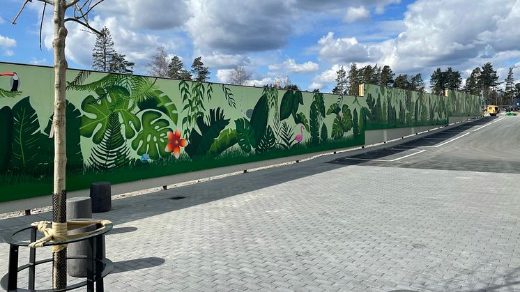 Spännande djur och färgglad grönska sätter färg på tillvaron intill Wallenstams nybyggnation Parkstråket vid Örnens väg i Haninge. Där monteras en 107 meter lång muralmålning på ett byggplank för att bidra till en trevlig utsikt för de nyinflyttade.