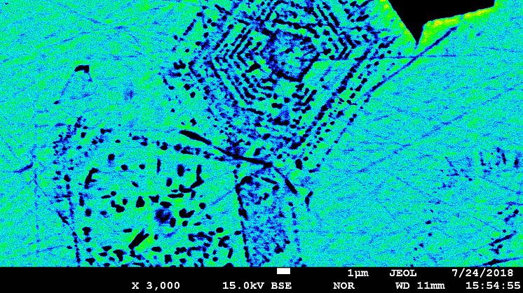 Färgad elektronmikroskopbild av en kemiskt zonerad magnetitkristall från den vulkaniska apatitjärnmalmen El Laco i chilenska Anderna.