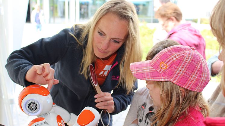 Immer dicht umlagert, vor allem von den Kindern: der Roboter "Annabell". Janine Breßler zeigt gerade, wie man mit ihm "Stein - Schere - Papier" spielt. © TH Wildau / Bernd Schlütter