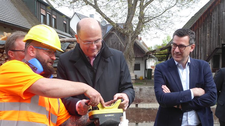 Albert Füracker, Bayerischer Staatsminister der Finanzen und für Heimat (Mitte) bedient eine Fräse, rechts Andreas Pfisterer, CEO von Deutsche Glasfaser.