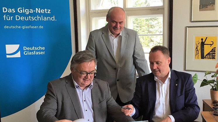 Ludwig Martin, Bürgermeister der Gemeinde Borsdorf (links) Michael Kölling, Regional Manager Deutsche Glasfaser Mitteldeutschland (rechts) und Projektmanager FttH Mitteldeutschland (hinten) besiegeln die Zusammenarbeit für den Glasfaser-Ausbau. (DG)