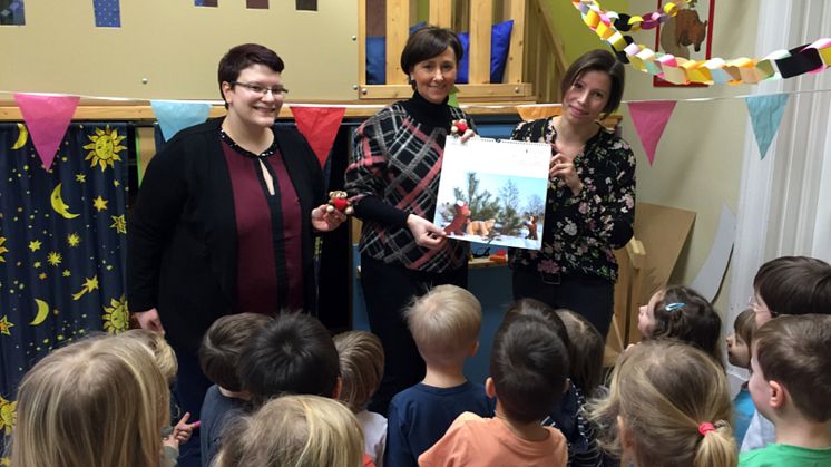 Anni Vogel, Constanze Weiß und Caro Birth umringt von den "Löwenkids", die staunend den Bärenherz-Kalender betrachten.