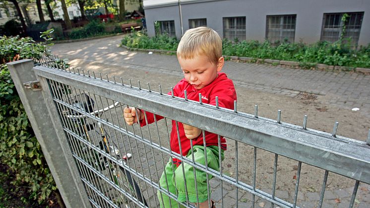 Junge klettert am Gitterzaun, Querformat