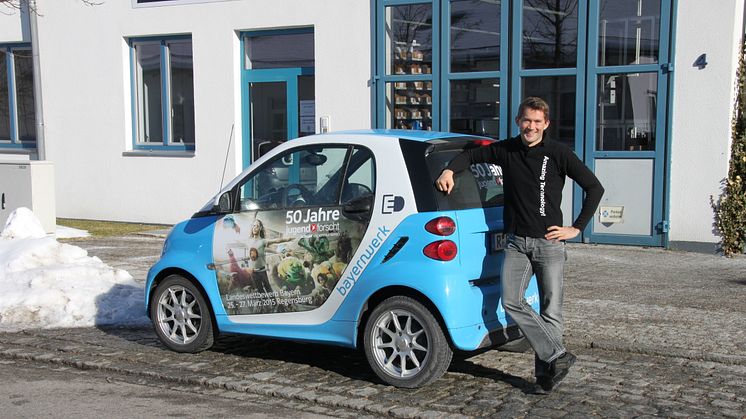 Foto: Mit dem „50 Jahre Jugend forscht E-Smart“ trifft das Patenunternehmen Bayernwerk ehemalige bayerische Preisträger, hier Daniel Gurdan, und lässt diese das Elektroauto signieren.