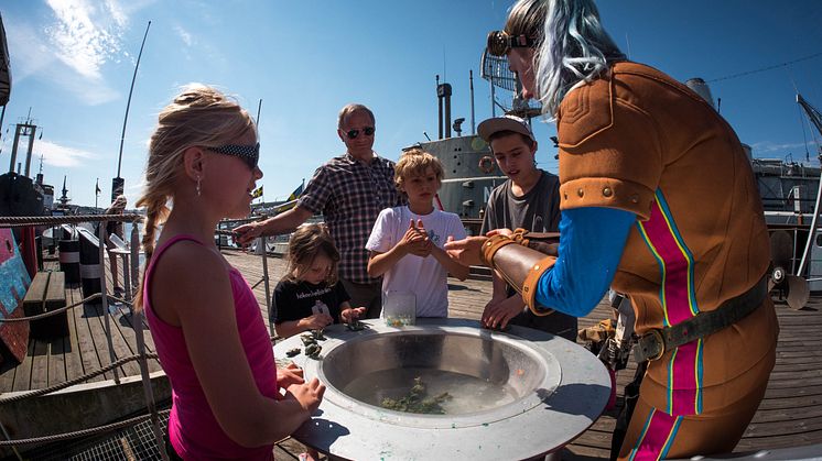 Maritimans maskot Virvelina gör vattenexperiment i havslabbet tillsammans med nyfikna besökare.