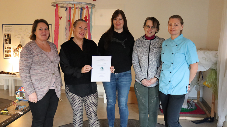 Personal på Fröhusets förskola i Kvidinge visar glatt upp diplomet med utmärkelsen Skola för hållbar utveckling som de tilldelats av Skolverket.