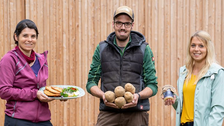 Anastasia Rempel vom Hofgut Richerode präsentiert den Richeröder Kartoffelpuffer. Arbeitsgruppenleiter David Straßer und Einrichtungsleiterin Jessica Walz zeigen besonders gut geeignete Kartoffeln der Sorte „Jelly“ und das hausgemachte Apfelmus. 