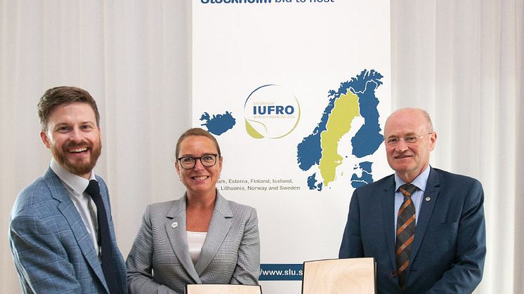 Projektledare Fredrik Ingemarson, SLU, koordinator Karin Hornay, Akademikonferens och SLU:s rektor Peter Högberg presenterar ansökningspärmen gjord i björkfanér. (Foto: Lucy Kibwota, SLU)